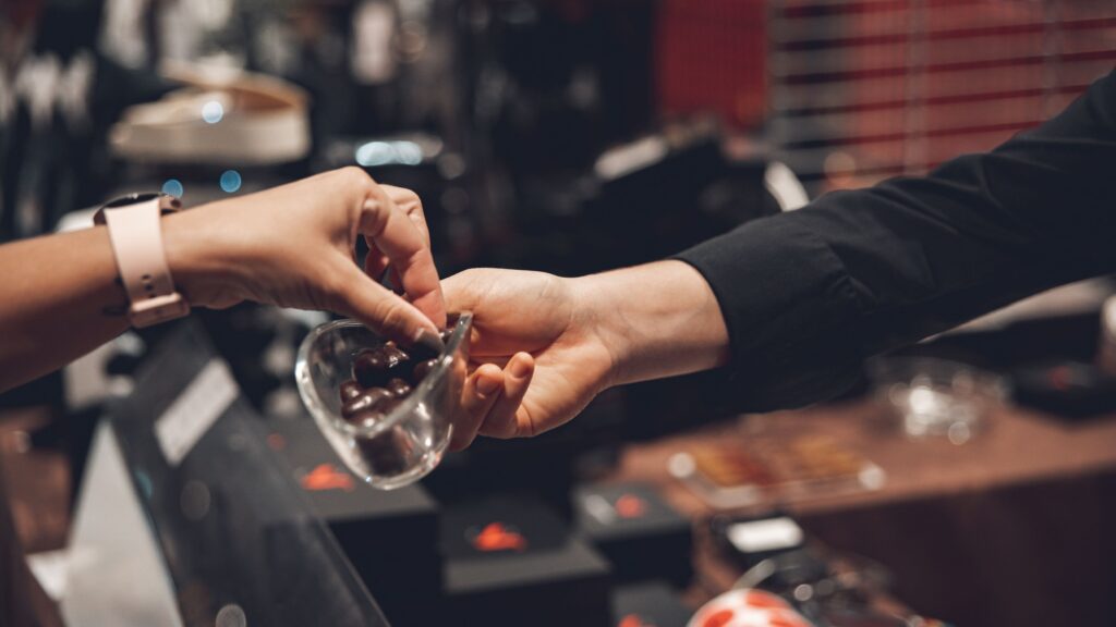 How to Stop Impulse Buying: 10 Proven Strategies Close-up of two people exchanging chocolates in a store setting.